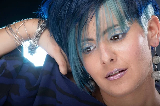 A woman with styled blue hair and matching makeup