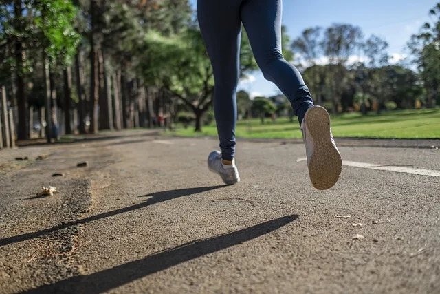A person wearing leggings and sneakers running outdoors on a path
