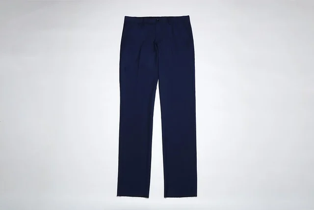 A pair of dark blue trousers laid flat on a white background