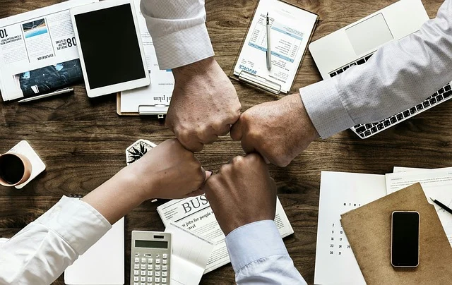 How to manage cash flow for a clothing business: Business colleagues doing a fist bump over a desk with financial documents