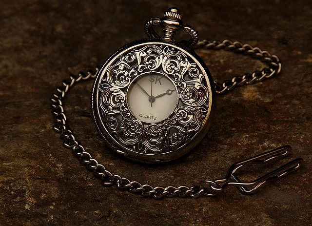An ornate vintage pocket watch with a chain on a stone surface
