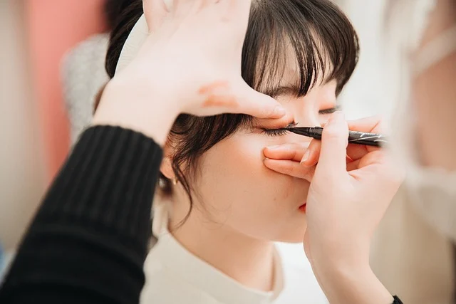A makeup artist applying liquid eyeliner to a woman's eyelid