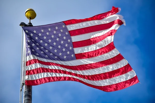 An American flag waving on a flagpole against a blue sky