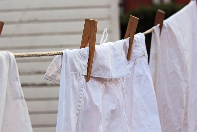White cotton laundry hanging on a clothesline with wooden pegs