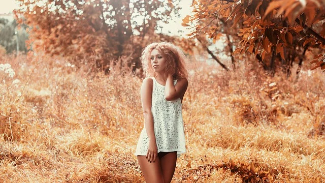 A woman in a short white sleeveless dress in a autumn field