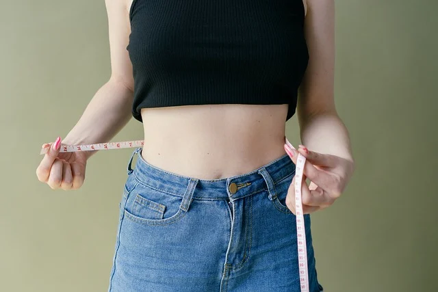 A woman measuring her waist with a tape measure