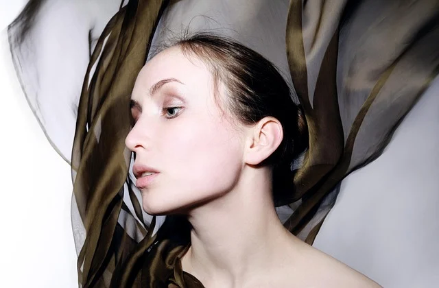 A woman posing with flowing sheer scarf fabric around her
