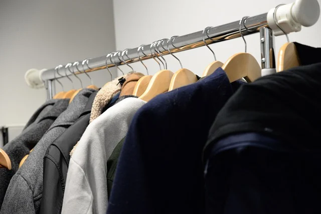 Coats and jackets hanging on wooden hangers on a clothing rack