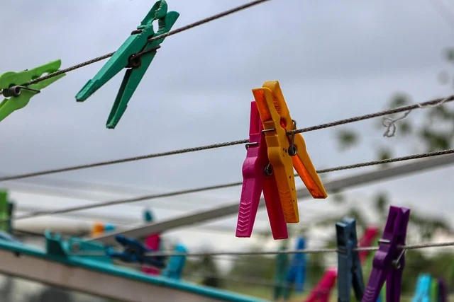 Colorful plastic clothespins hanging on a clothesline outdoors