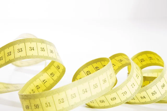 A coiled yellow measuring tape on a white background