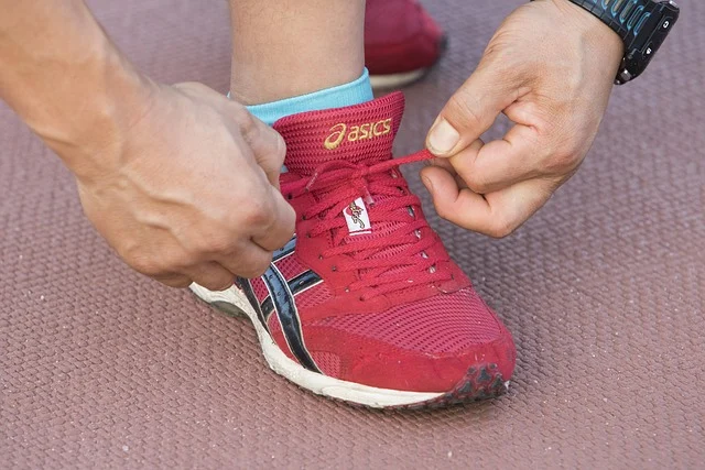 A person tying the laces on a red running shoe