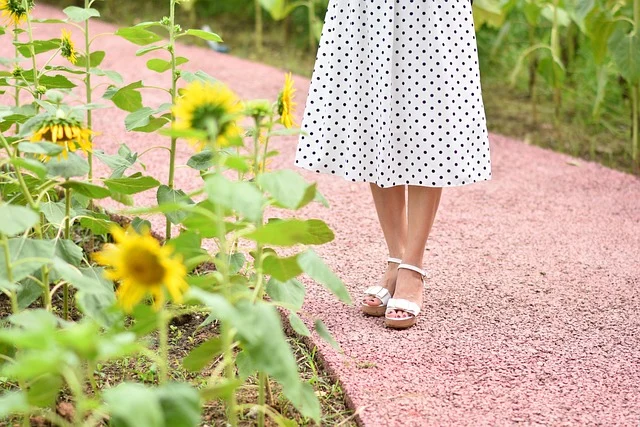 A woman wearing a white dress with black polka dots standing outdoors