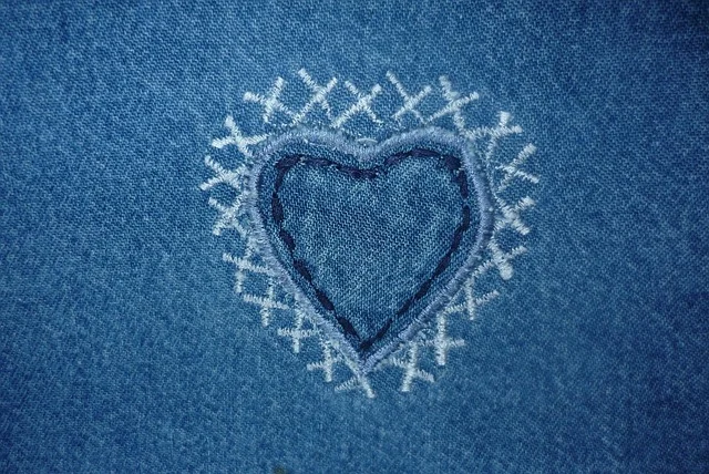Embroidered heart design on blue denim fabric