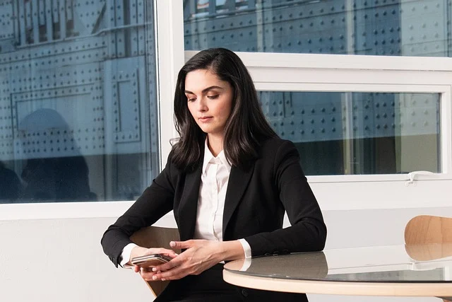 Frankie shop: A woman wearing a black blazer and white shirt holding a phone
