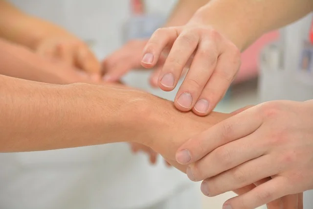 Hands examining a patient's wrist during a medical skin checkup