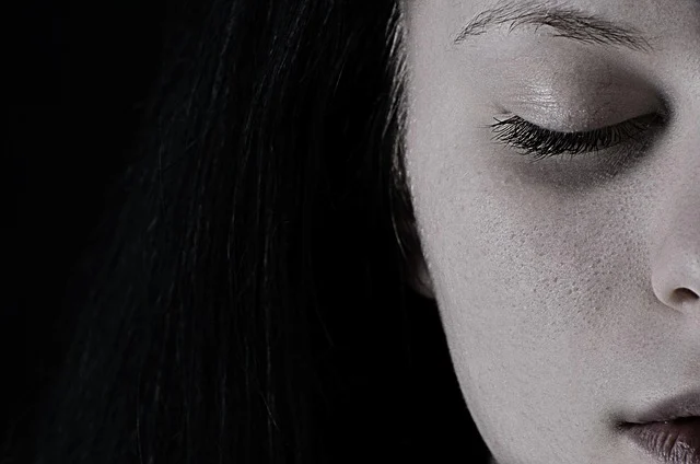 A close-up portrait of a woman's face with closed eyes