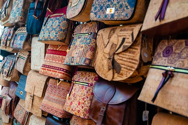 A display of patterned and cork handbags hanging on a wall