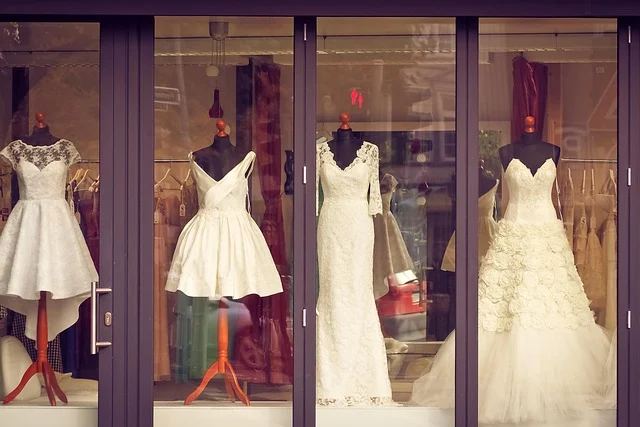 Mannequins displaying white dresses in a shop window