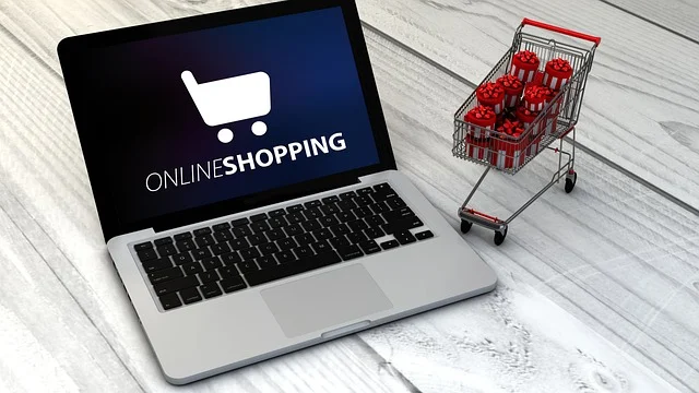 A laptop displaying online shopping text next to a small shopping cart