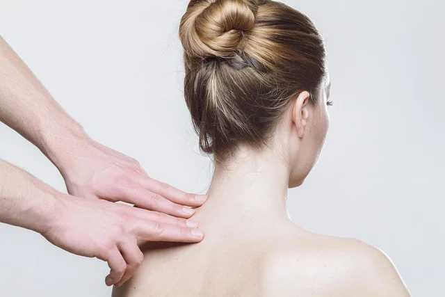 Hands touching a woman's neck and shoulder from behind