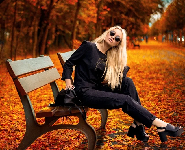 Blonde woman in a black outfit sitting on a park bench