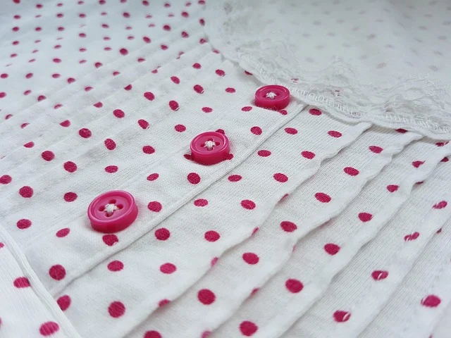Close-up of white fabric with pink polka dots and buttons