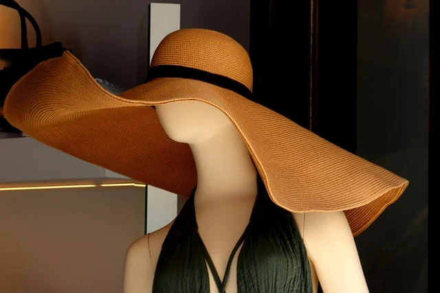 A mannequin wearing a wide-brimmed straw hat in a fashion display