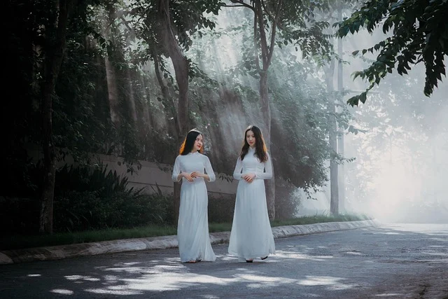 Two women wearing long white dresses walking outdoors