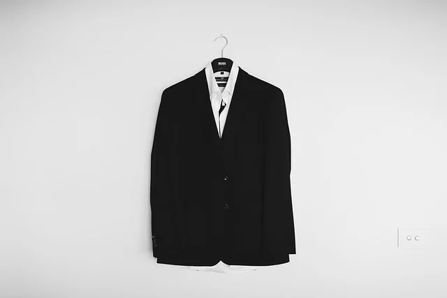A black suit jacket and white shirt hanging on a hanger