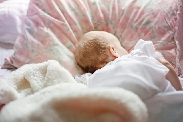 A baby lying down on a bed next to a pillow
