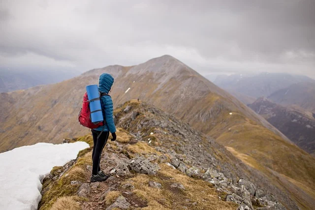 A hiker with a backpack standing on a rugged mountain ridge