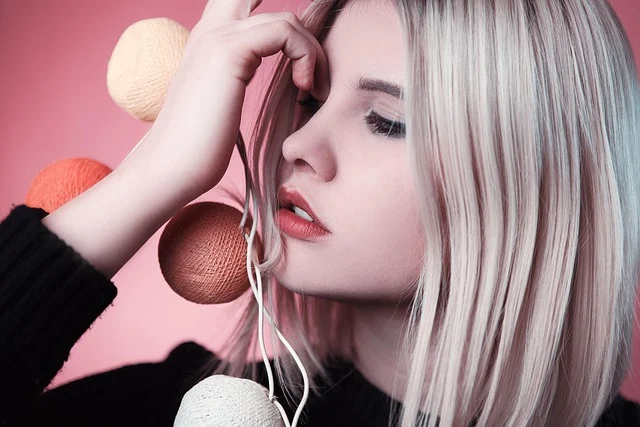 A woman with platinum blonde hair holding string lights