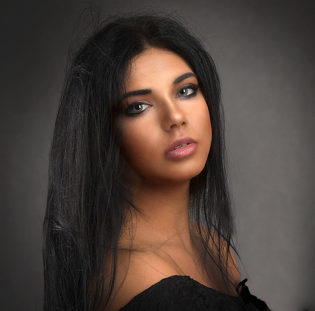 Woman with long, pin-straight dark brown hair with a middle part, looking confident and elegant. (straight hair fashion)