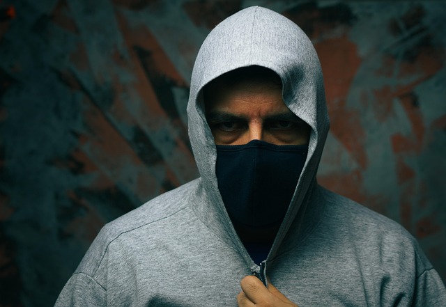 A person wearing a grey hoodie and face mask