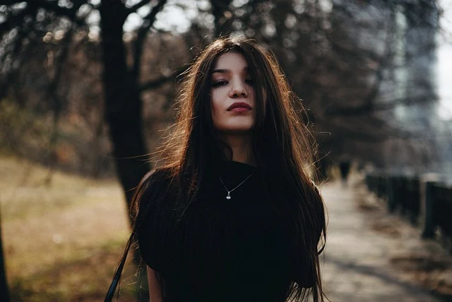 A young woman wearing a simple pendant necklace and black top
