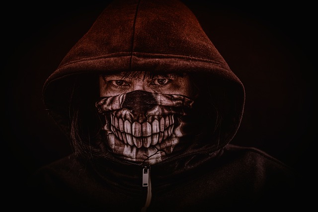 A person wearing a hoodie and a skull print face mask