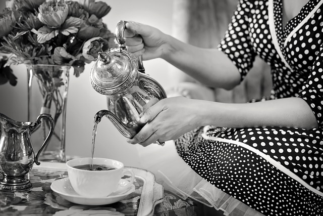 A woman wearing a black and white polka dot dress pouring tea