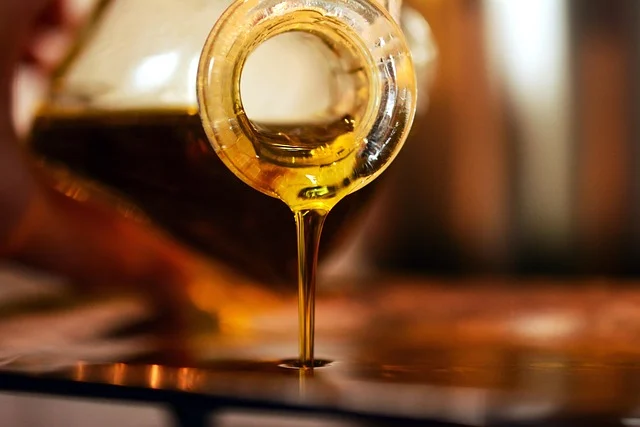 Golden oil pouring from a glass bottle