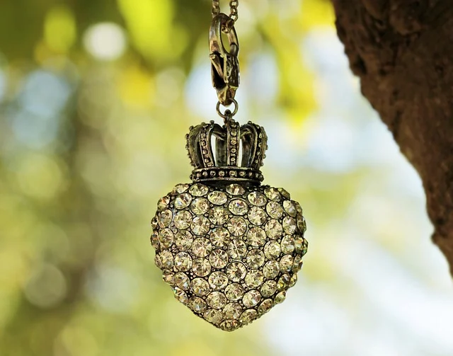 A heart-shaped crystal pendant with a crown top hanging outdoors