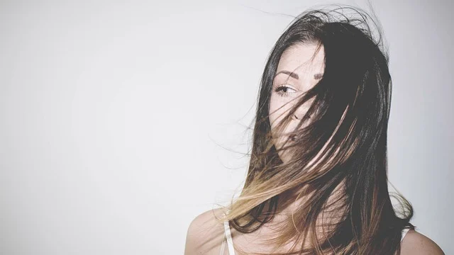 A woman with her long dark hair blowing across her face