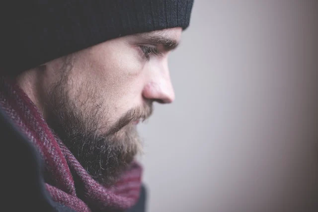 Close-up side profile of a man with a beard wearing a beanie