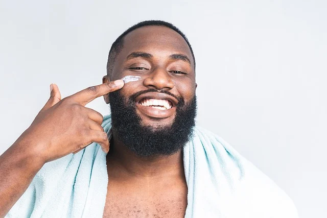 A smiling man applying cream to his cheek
