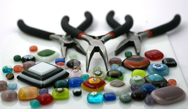 Craft pliers surrounded by colorful glass beads and cabochons