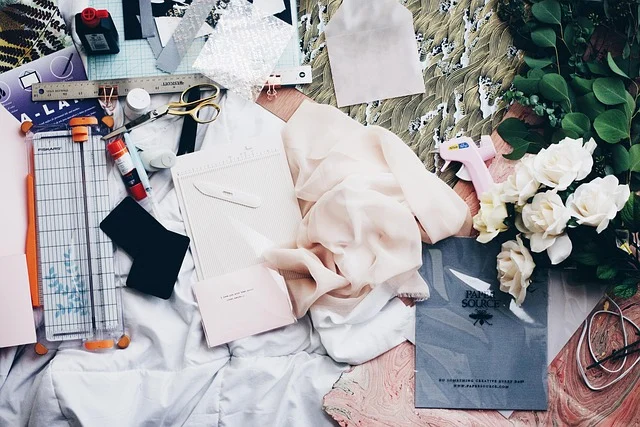 A flat lay of crafting tools, fabric, paper, and flowers