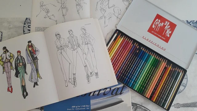 How to fashion sketch: Fashion sketches in books next to a tin of colored pencils
